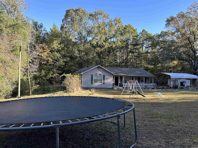 view of front facade with a carport, a trampoline, and a front lawn