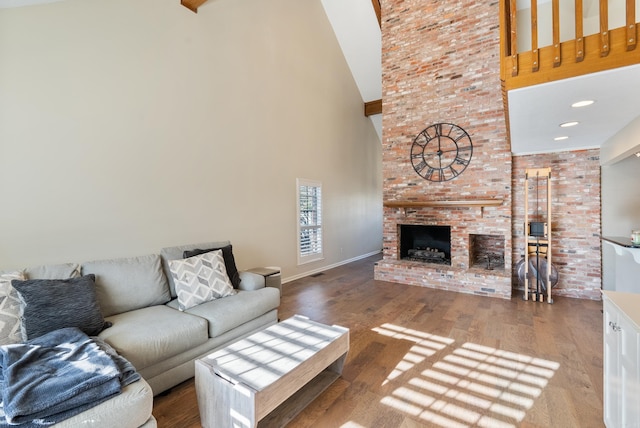 living room with hardwood / wood-style floors, a high ceiling, and a brick fireplace