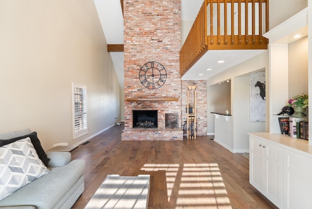 living room with hardwood / wood-style floors, a high ceiling, and a brick fireplace