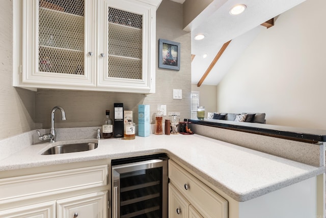 bar featuring cream cabinets, vaulted ceiling with beams, beverage cooler, and sink