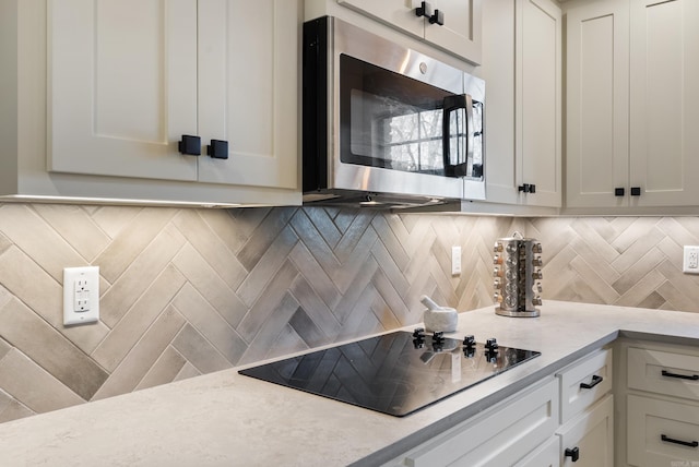 kitchen featuring white cabinets, black electric stovetop, and tasteful backsplash