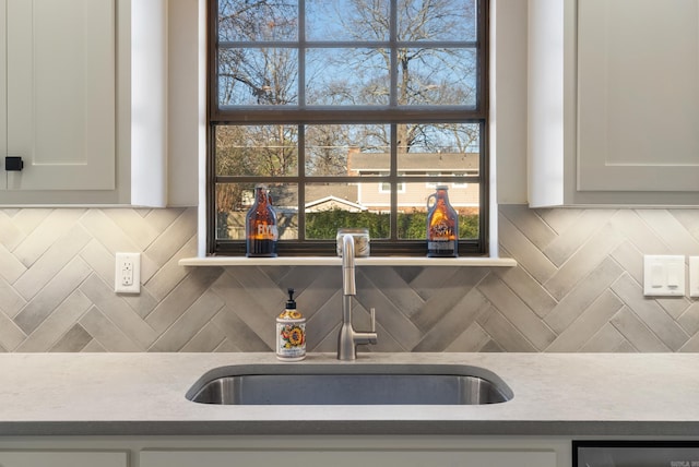 kitchen featuring tasteful backsplash, white cabinetry, and sink