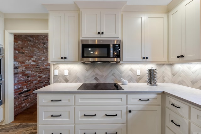 kitchen featuring backsplash, black electric cooktop, and white cabinets