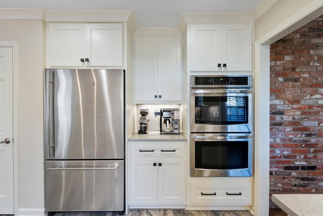 kitchen with light stone countertops, white cabinetry, and appliances with stainless steel finishes