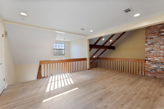 additional living space featuring light hardwood / wood-style flooring and lofted ceiling with beams