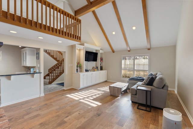 living room featuring beamed ceiling, high vaulted ceiling, and light wood-type flooring