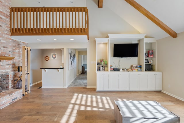 unfurnished living room featuring beamed ceiling, light hardwood / wood-style floors, and high vaulted ceiling