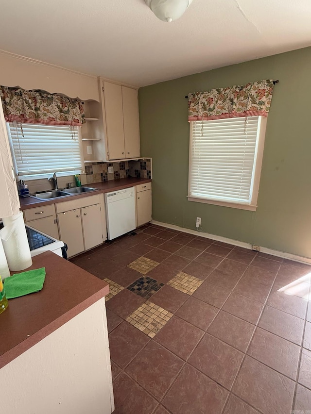 kitchen featuring sink, stove, white dishwasher, decorative backsplash, and dark tile patterned flooring