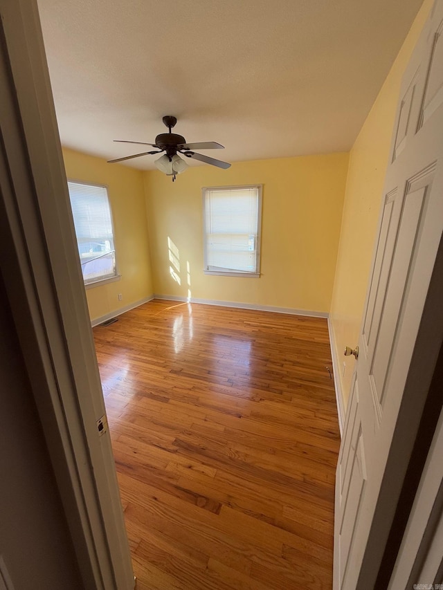 unfurnished room with ceiling fan, a healthy amount of sunlight, and light wood-type flooring