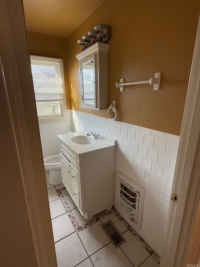 bathroom with vanity, tile patterned flooring, toilet, tile walls, and heating unit