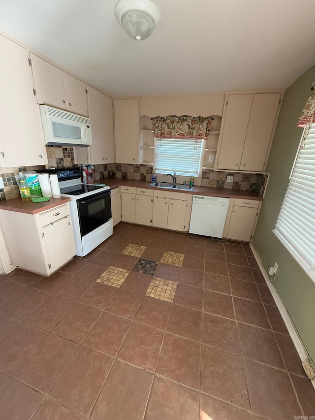 kitchen with white appliances, backsplash, cream cabinets, sink, and dark tile patterned floors