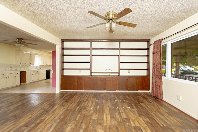 spare room featuring ceiling fan, wooden walls, dark wood-type flooring, and a textured ceiling