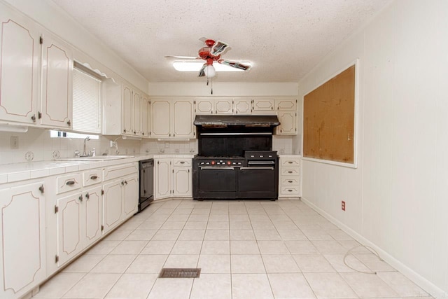 kitchen featuring sink, a textured ceiling, black dishwasher, tile counters, and high quality stove