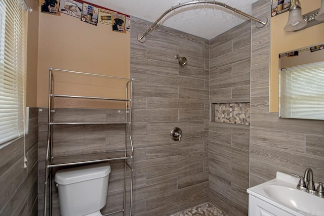 bathroom with a tile shower, vanity, a textured ceiling, and toilet