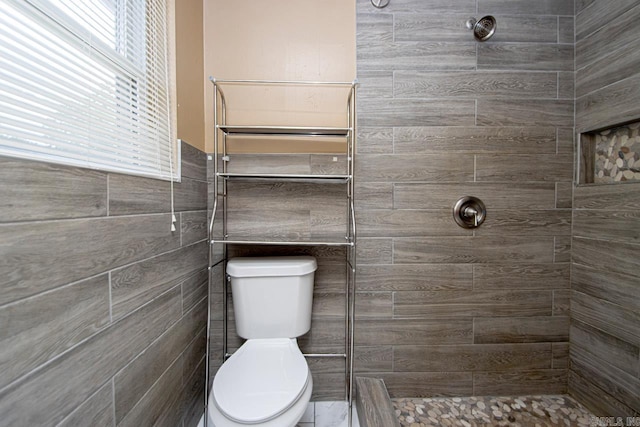 bathroom with tiled shower, tile walls, and toilet