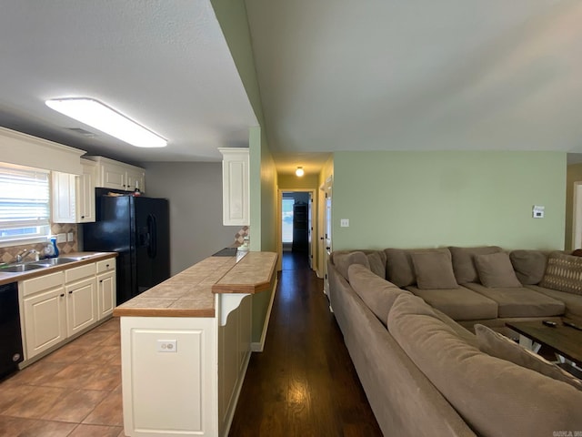 kitchen featuring black appliances, tile counters, white cabinets, and sink