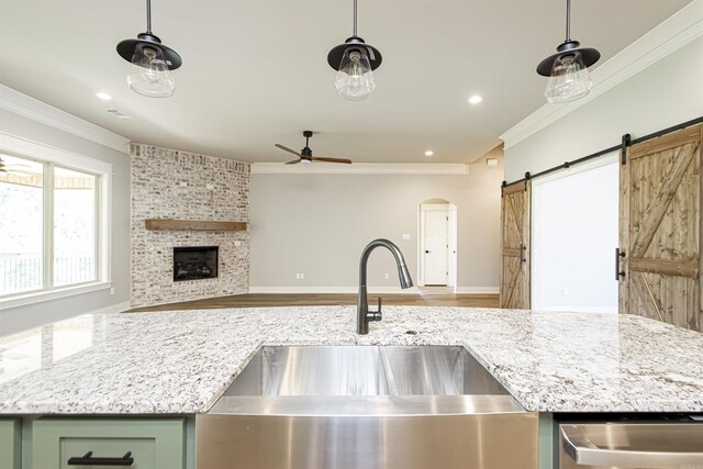 kitchen with a barn door, sink, green cabinets, and hanging light fixtures