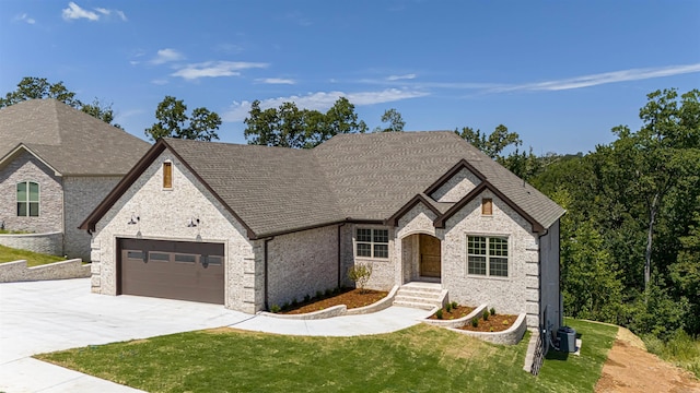 view of front of house featuring a front lawn, central AC unit, and a garage