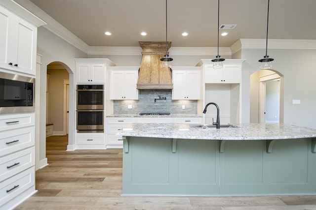 kitchen featuring a spacious island, sink, built in microwave, decorative light fixtures, and stainless steel double oven