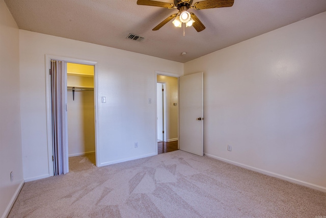 unfurnished bedroom with ceiling fan, light carpet, and a closet