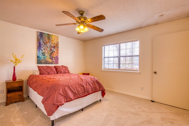 bedroom featuring ceiling fan, light colored carpet, and a textured ceiling