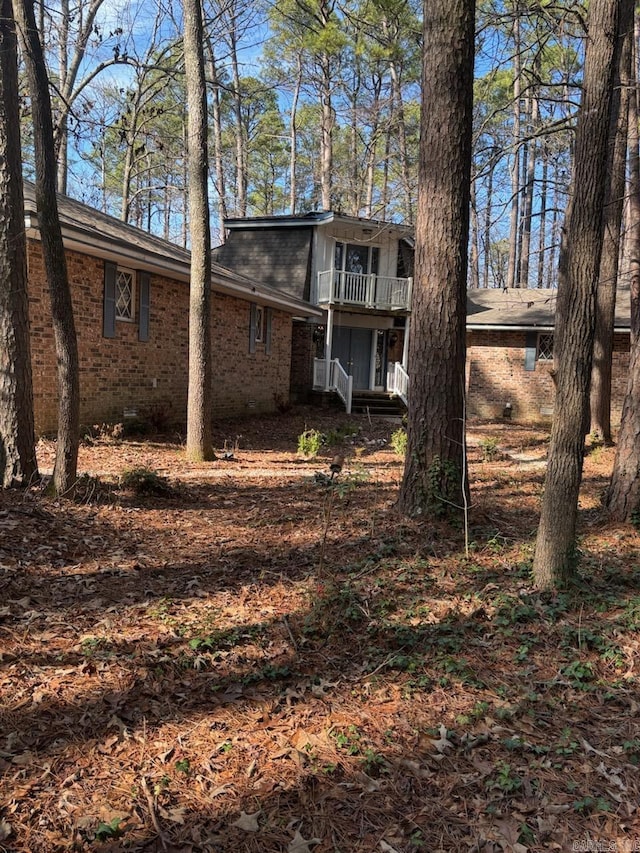 back of property with crawl space, brick siding, and a balcony