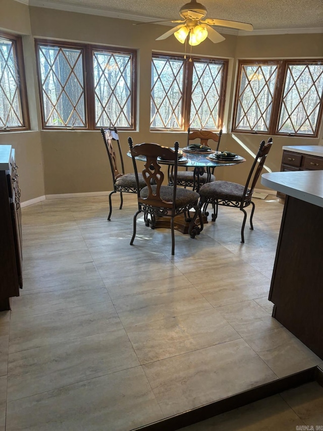 dining space with a textured ceiling, ceiling fan, and crown molding