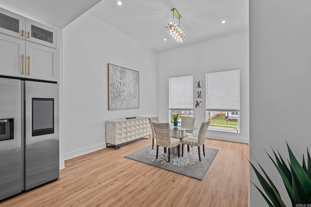 dining space with light hardwood / wood-style floors and a notable chandelier