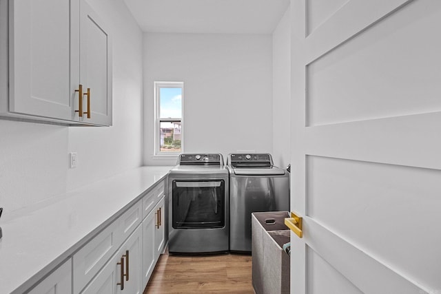 washroom with washer and dryer, cabinets, and light hardwood / wood-style flooring