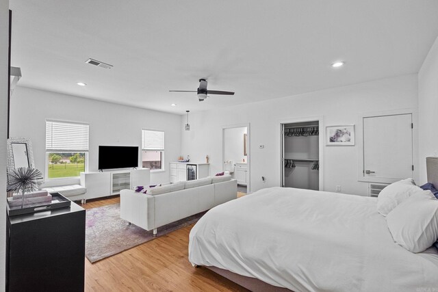 bedroom with connected bathroom, ceiling fan, a spacious closet, light hardwood / wood-style floors, and a closet