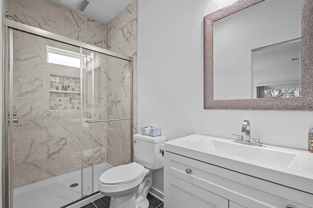 bathroom with vanity, toilet, and a shower with door