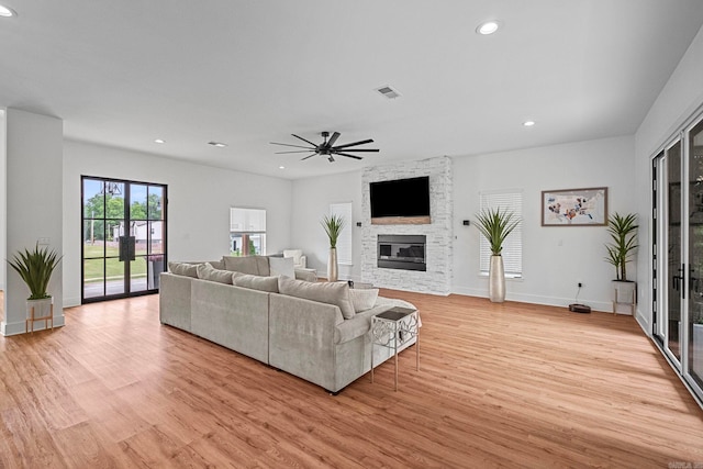 living room with ceiling fan, a fireplace, and light hardwood / wood-style flooring