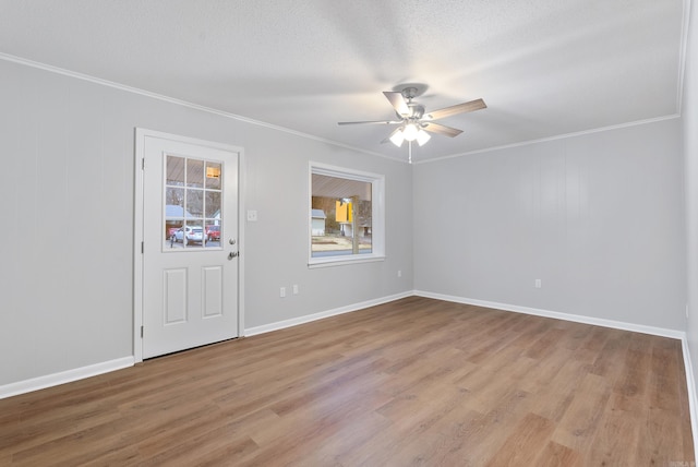 empty room with a textured ceiling, light wood-type flooring, ceiling fan, and ornamental molding