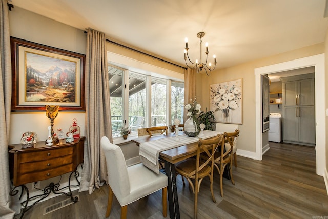 dining room with washer / dryer, dark wood-type flooring, and a notable chandelier