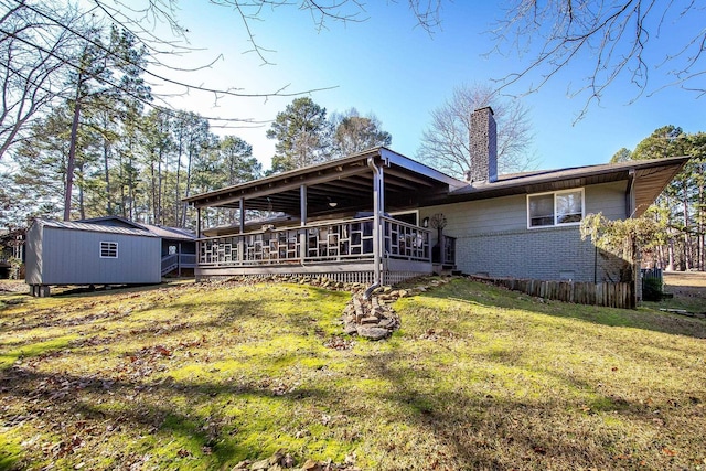 rear view of property with a storage unit, a deck, and a yard