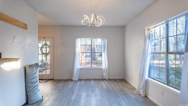 doorway to outside featuring a notable chandelier, plenty of natural light, and hardwood / wood-style floors