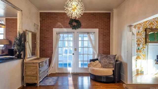 doorway with crown molding, dark hardwood / wood-style flooring, brick wall, and a notable chandelier