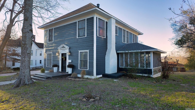 view of front facade with a lawn and a sunroom