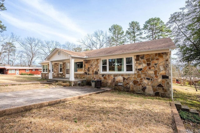 view of front of home with stone siding, a porch, and a front lawn