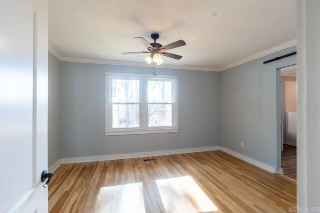 spare room with light wood-type flooring, visible vents, ornamental molding, baseboards, and ceiling fan