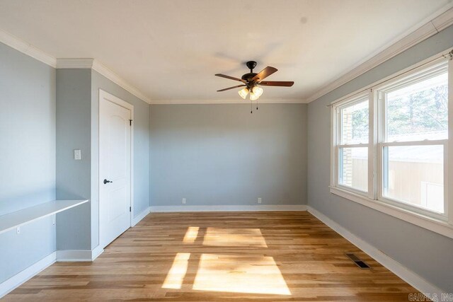 spare room featuring baseboards, light wood-style flooring, a ceiling fan, and ornamental molding