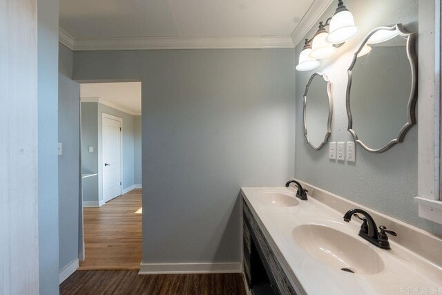 full bath featuring ornamental molding, wood finished floors, baseboards, and a sink