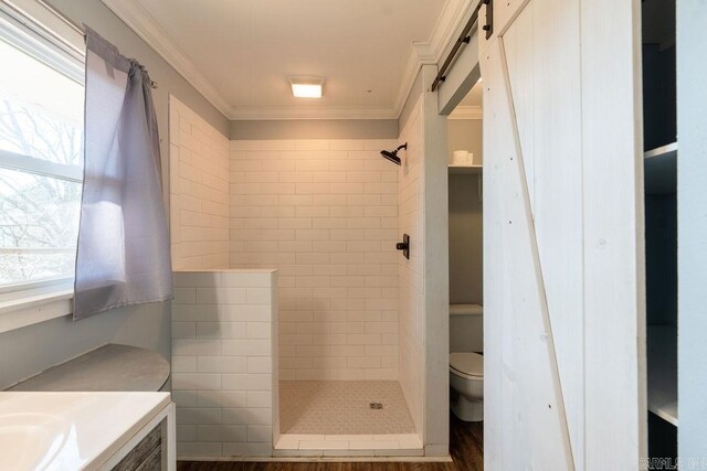 bathroom with tiled shower, toilet, vanity, and crown molding