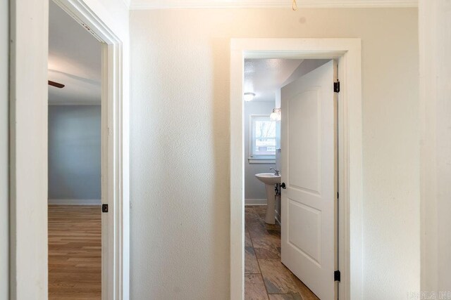 corridor featuring baseboards, wood finished floors, and a textured wall