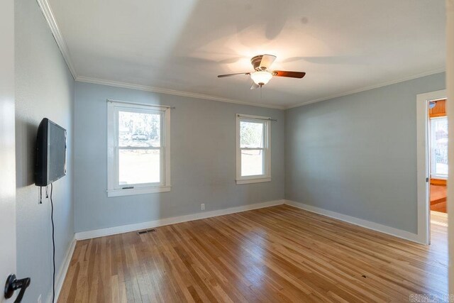 empty room featuring a ceiling fan, crown molding, wood finished floors, and baseboards