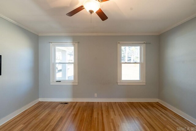 unfurnished room featuring visible vents, baseboards, wood finished floors, and ornamental molding