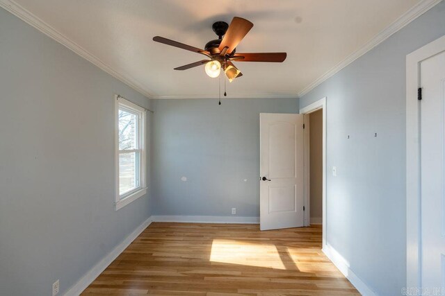 empty room with ceiling fan, baseboards, crown molding, and light wood-style floors