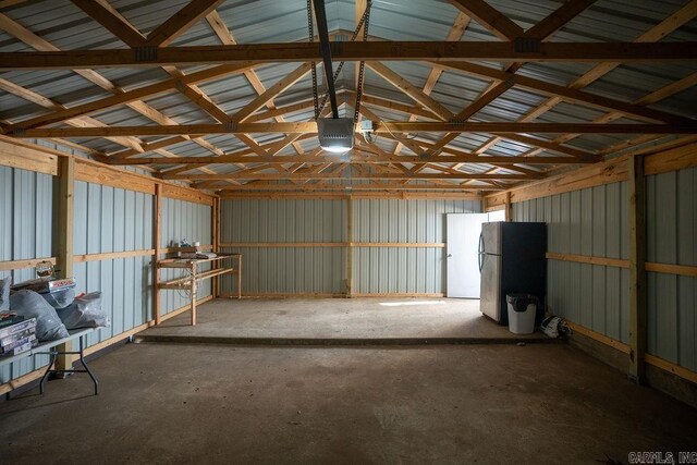 garage featuring a garage door opener, metal wall, and freestanding refrigerator