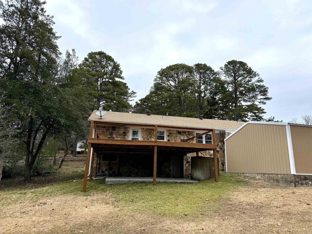 back of property featuring a deck, a patio area, a lawn, and stone siding