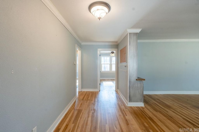 corridor with wood finished floors, baseboards, and ornamental molding